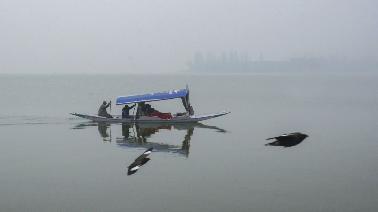 The majestic Himalayan mountains that usually stand tall and proud in the distance are obscured by the low-lying fog. Their snow-covered peaks may appear as faint shadows, barely visible through the haze, giving the entire landscape a dreamlike quality. (In Pic: Tourists take a Shikara ride at the Dal Lake on a foggy winter afternoon, in Srinagar on Saturday)